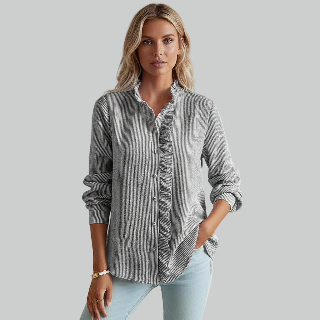 Model posing in a gray button-down shirt with rolled sleeves, styled casually with light denim jeans.