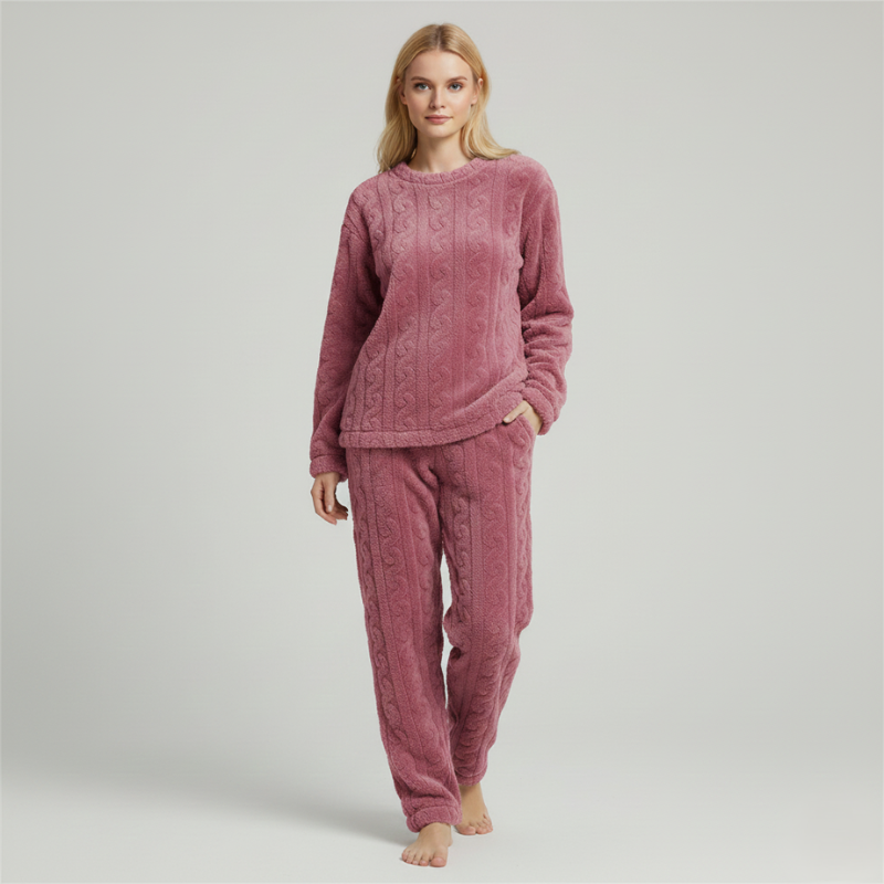 Woman wearing a pink fleece lounge set with a warm textured top and matching pants in soft studio lighting.